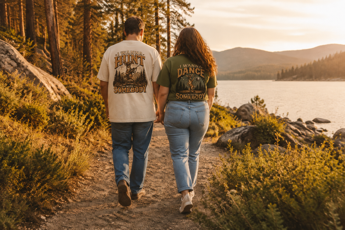 Couple wearing I Wanna Hunt and I Wanna Dance graphic T-shirts beside a lake